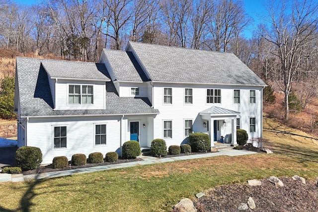 colonial-style house with a shingled roof and a front yard