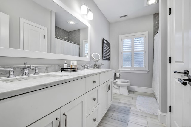 full bathroom with toilet, a sink, visible vents, baseboards, and double vanity