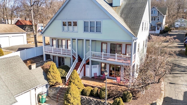 rear view of house featuring a shingled roof, stairway, a porch, a chimney, and a garage