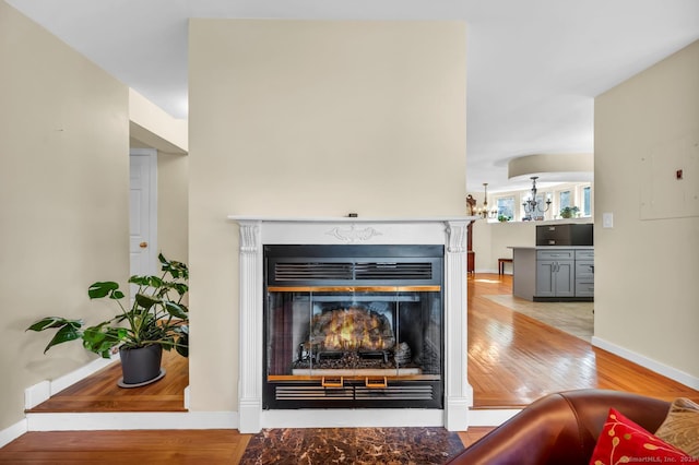 room details featuring a fireplace with flush hearth, wood finished floors, and baseboards