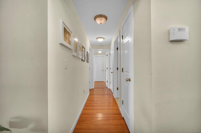 hallway with light wood-type flooring and baseboards