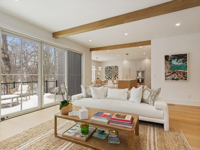 living room with recessed lighting, beam ceiling, light wood-style flooring, and baseboards