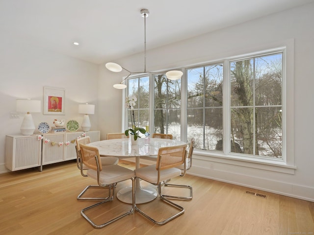 dining room featuring light wood-style flooring, visible vents, and baseboards