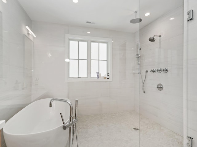 full bathroom featuring a freestanding tub, a shower stall, and visible vents