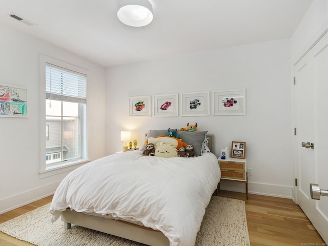 bedroom with visible vents, light wood-style flooring, and baseboards