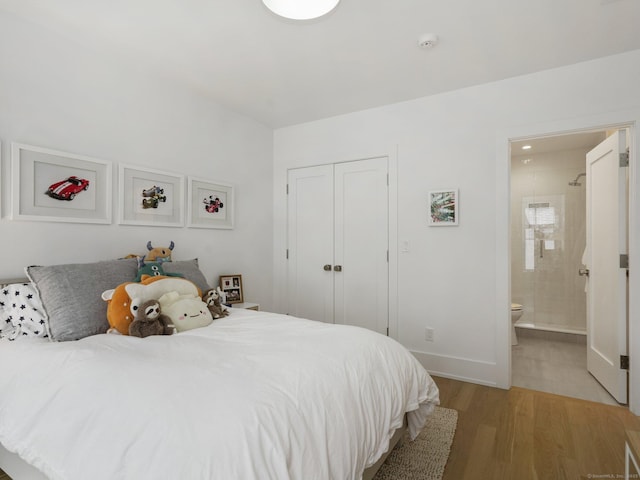 bedroom with light wood-style flooring, baseboards, a closet, and ensuite bathroom