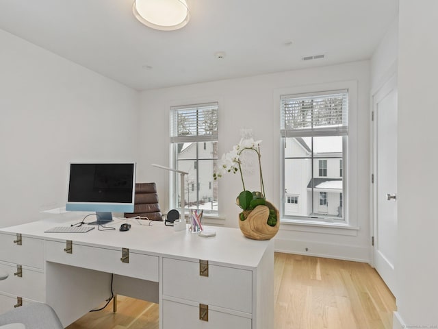 office space with light wood-style floors, baseboards, and visible vents