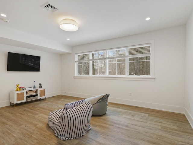 sitting room with light wood-type flooring, a healthy amount of sunlight, baseboards, and visible vents