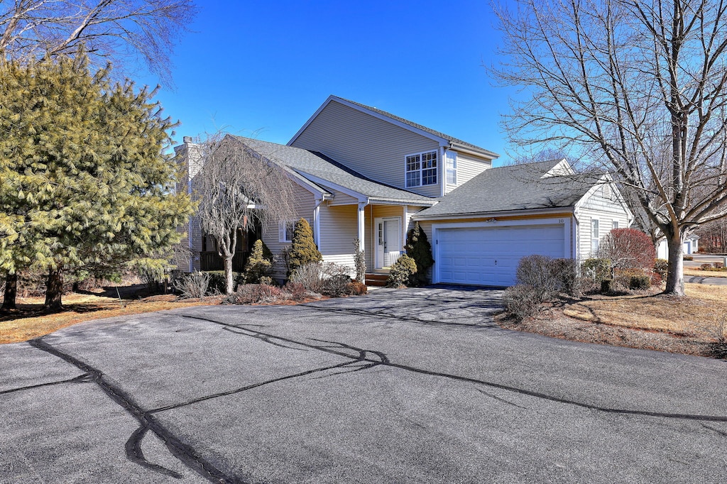 traditional-style home featuring a garage, aphalt driveway, and a chimney