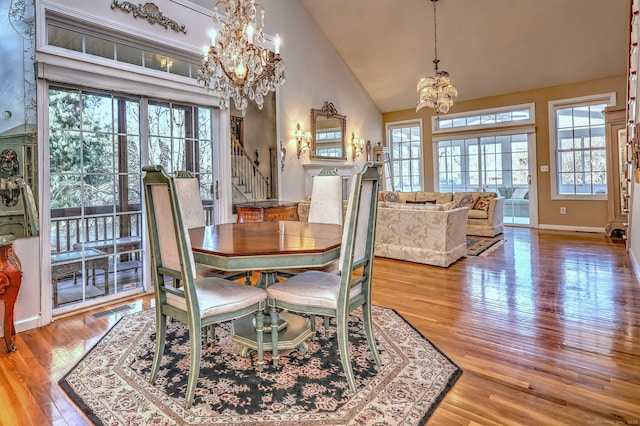 dining area featuring visible vents, an inviting chandelier, wood finished floors, high vaulted ceiling, and stairs