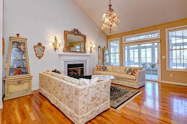 living room featuring a glass covered fireplace, baseboards, visible vents, and light wood finished floors