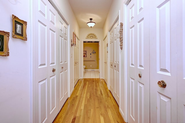 corridor featuring light wood-style floors and baseboards