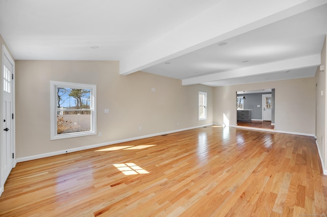 unfurnished living room with light wood-type flooring, lofted ceiling with beams, and baseboards