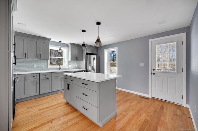 kitchen featuring light wood-style floors, gray cabinets, visible vents, and stainless steel fridge with ice dispenser
