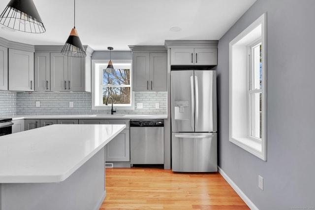 kitchen with stainless steel appliances, a sink, and gray cabinetry