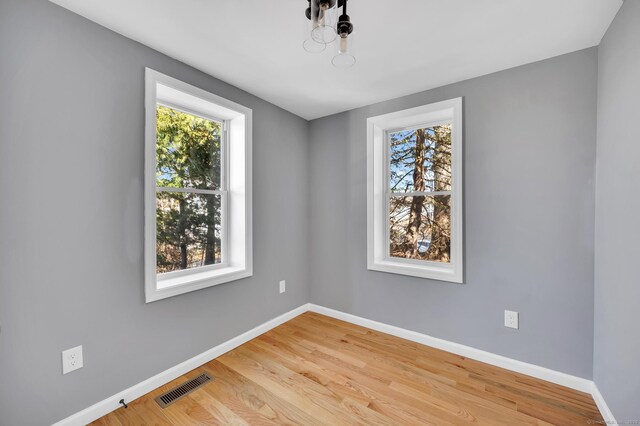 spare room with visible vents, baseboards, and wood finished floors