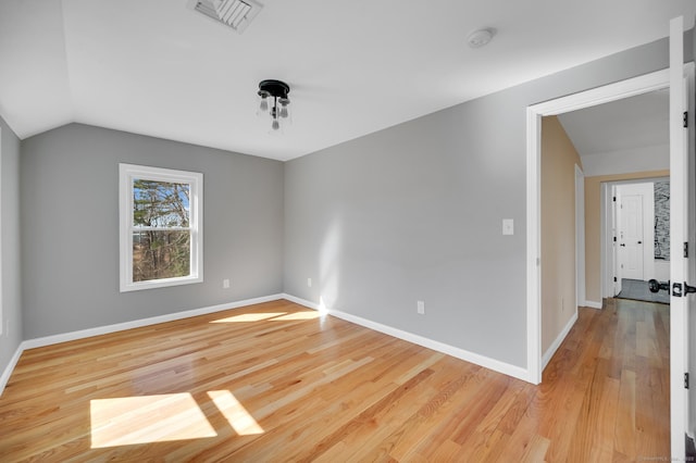 spare room with vaulted ceiling, baseboards, visible vents, and light wood-style floors