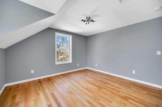 bonus room featuring light wood-type flooring, lofted ceiling, and baseboards
