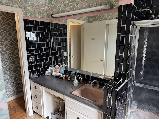 bathroom with an enclosed shower, vanity, baseboards, and wallpapered walls