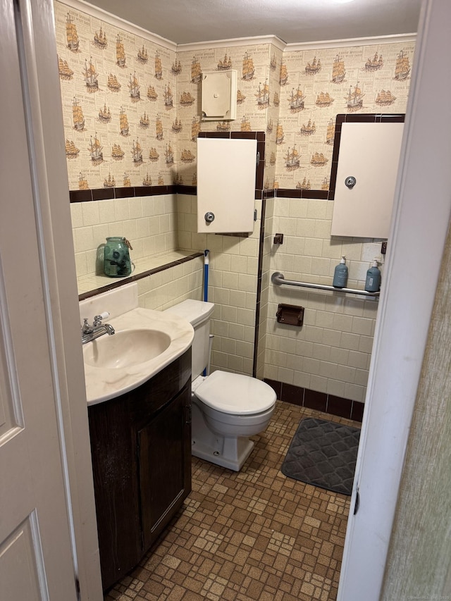 bathroom with a wainscoted wall, vanity, toilet, and wallpapered walls