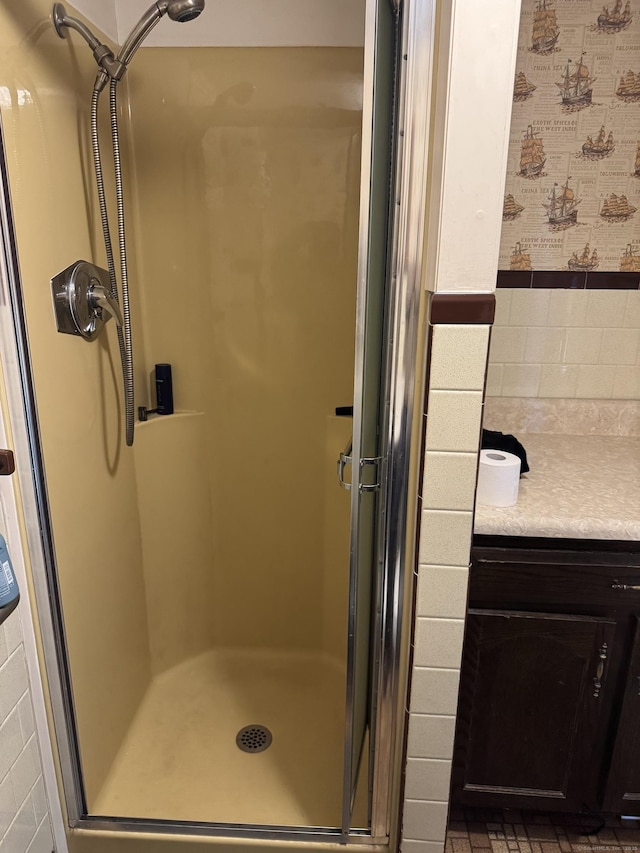 bathroom featuring a stall shower, vanity, and wallpapered walls