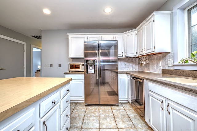 kitchen featuring visible vents, white cabinetry, stainless steel appliances, and a sink