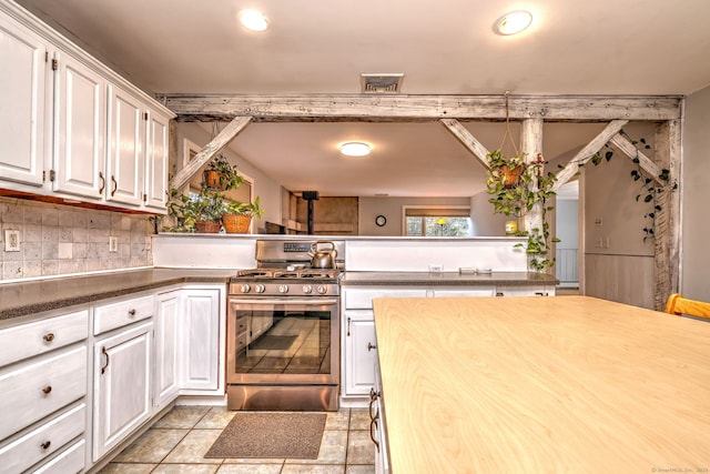 kitchen featuring white cabinets, stainless steel gas range oven, visible vents, and decorative backsplash