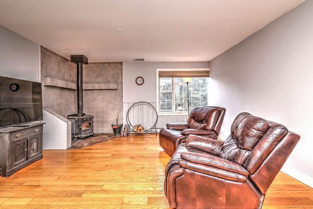 living room featuring a wood stove, visible vents, and wood finished floors