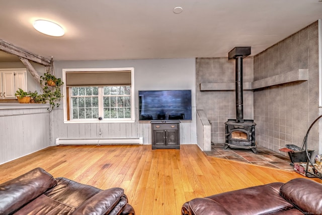 living room with light wood-style floors, a baseboard radiator, and a wood stove