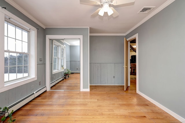 unfurnished room with a wainscoted wall, a baseboard radiator, light wood-style flooring, and crown molding