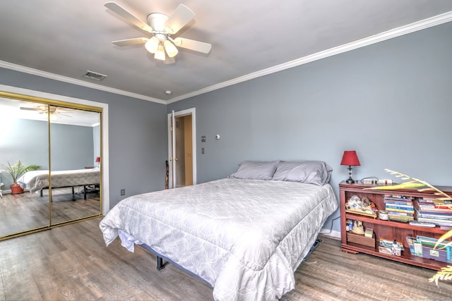 bedroom with visible vents, a ceiling fan, wood finished floors, crown molding, and a closet