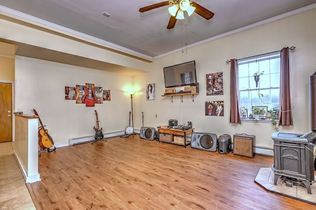 exercise area with a wood stove, light wood-style floors, a baseboard radiator, and crown molding