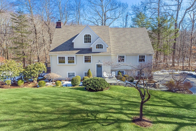 view of front of home with a front lawn, a chimney, and a shingled roof