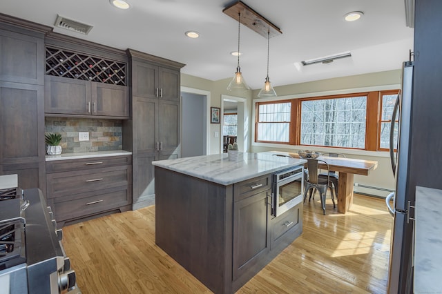 kitchen featuring visible vents, decorative backsplash, a baseboard radiator, stainless steel appliances, and dark brown cabinets