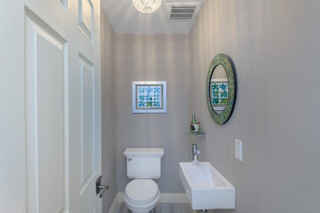 bathroom featuring toilet, baseboards, visible vents, and a sink