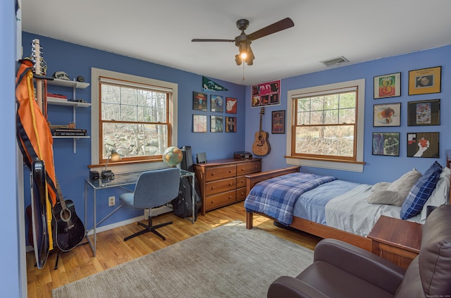 bedroom featuring a ceiling fan, wood finished floors, visible vents, and baseboards