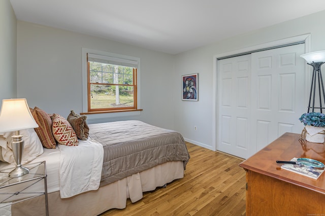 bedroom featuring a closet, light wood-style flooring, and baseboards