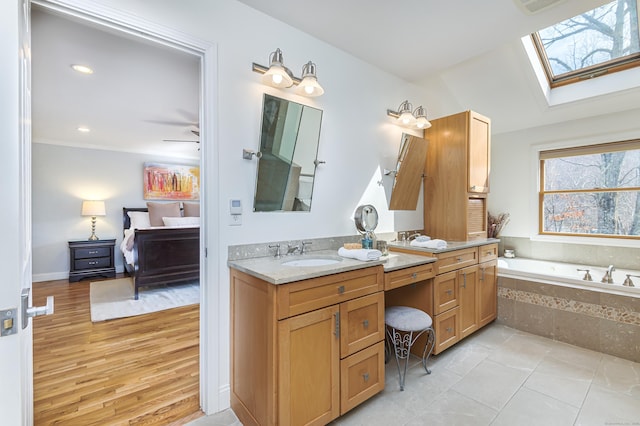 full bathroom with a garden tub, a skylight, wood finished floors, a sink, and double vanity