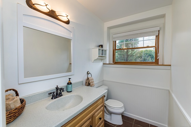 bathroom featuring tile patterned flooring, a wainscoted wall, vanity, and toilet