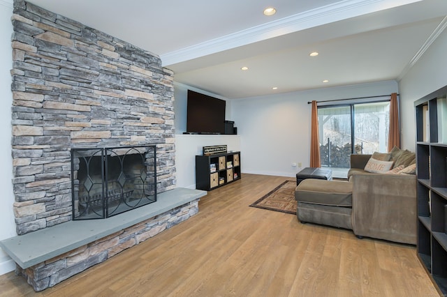 living room featuring ornamental molding, a stone fireplace, baseboards, and wood finished floors