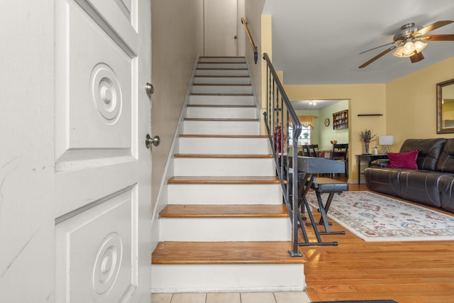 stairs featuring ceiling fan and wood finished floors