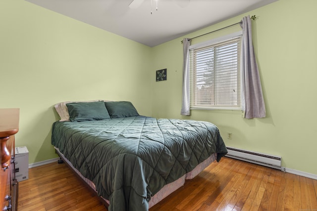 bedroom with a baseboard heating unit, hardwood / wood-style flooring, baseboards, and ceiling fan