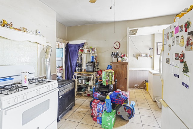 kitchen featuring light tile patterned floors, ceiling fan, white appliances, and a wainscoted wall