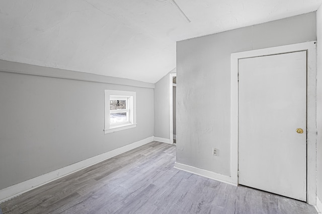 unfurnished room featuring vaulted ceiling, baseboards, and wood finished floors