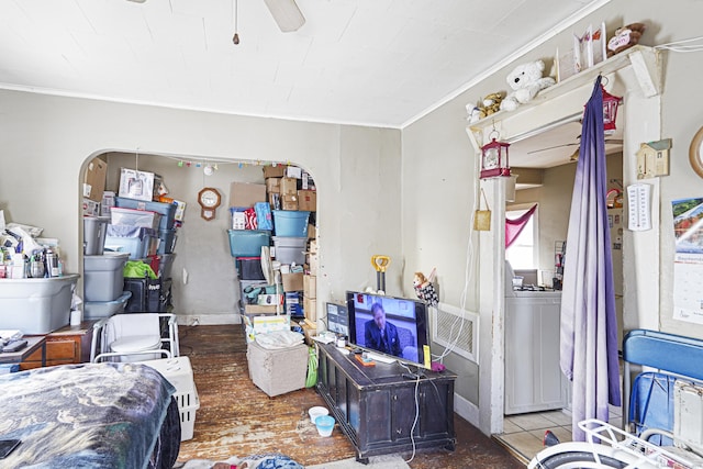 bedroom featuring washer / dryer, baseboards, arched walkways, ornamental molding, and wood finished floors