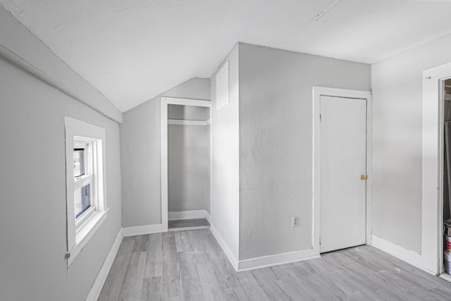 unfurnished bedroom featuring light wood-type flooring, baseboards, a closet, and lofted ceiling