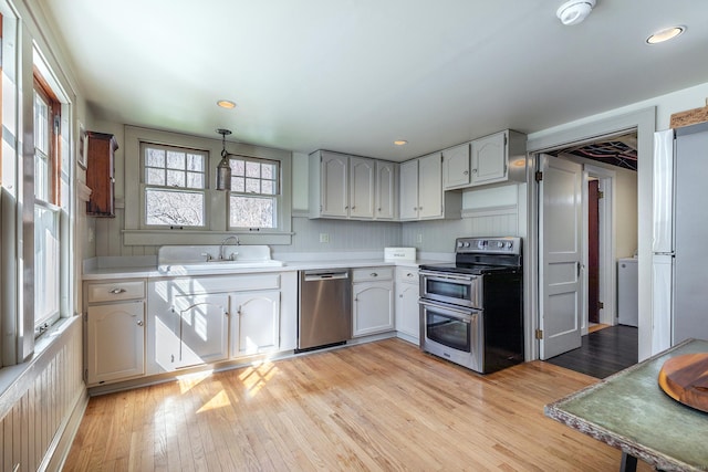 kitchen with a sink, light countertops, light wood-style floors, and stainless steel appliances