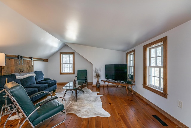 living room featuring wood-type flooring, visible vents, plenty of natural light, and vaulted ceiling