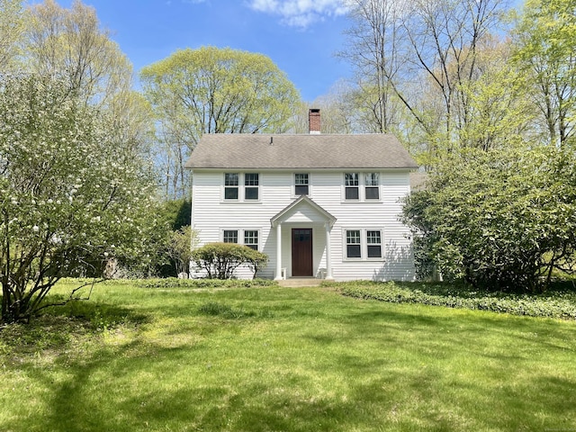 colonial house featuring a chimney and a front lawn
