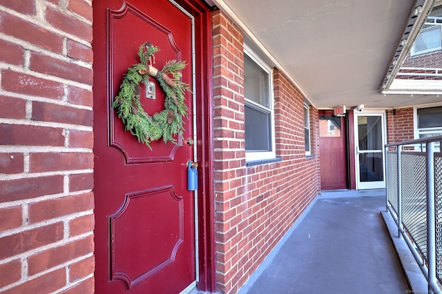 doorway to property featuring covered porch and brick siding